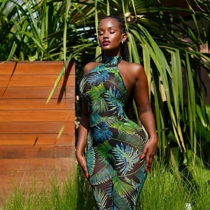 Dettaglio della tuta scollata in mesh trasparente con stampa tropicale di palme