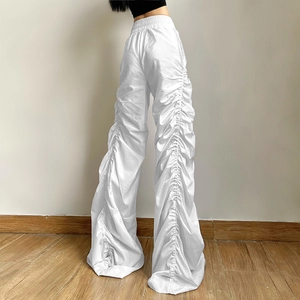Detail view of white high-waisted wide-leg pants featuring stylish ruched fabric texture