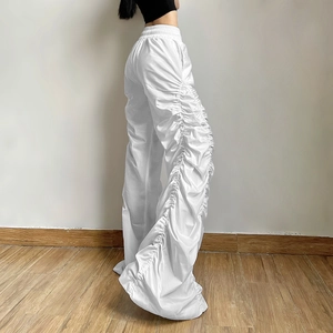 Detail of high-waist white wide-leg trousers with vertical ruched pleats and elastic waist