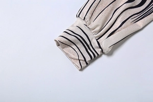 Detailed view of elastic cuffs with black wavy vertical stripes on beige fabric