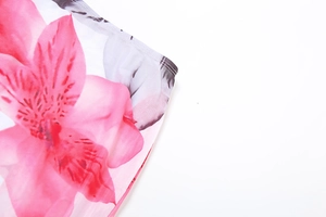 Close-up of semi-transparent mesh fabric with pink floral prints and fine edge stitching