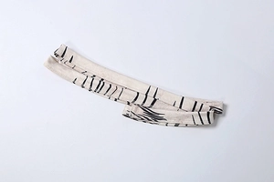Detail of off-white fabric strap with black abstract branch patterns and fine stitching