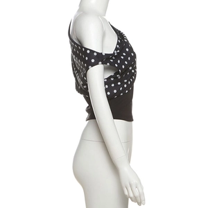 Detail of a one-shoulder black and white polka dot crop top showing side fit and texture
