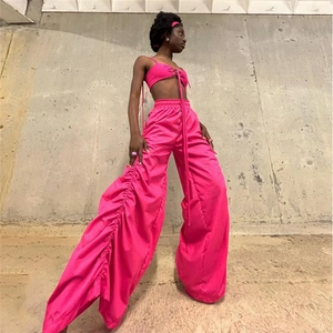 Detail of high-waist ruched trousers and halter crop top in vibrant neon pink