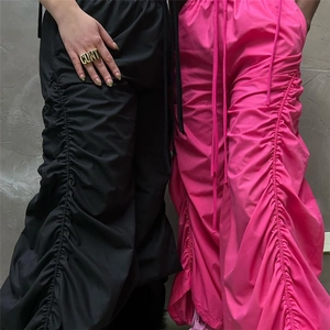Detail of ruched drawstring parachute pants in vibrant magenta and black fabric