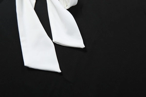 Detail of the black bodysuit featuring a white chiffon halter tie and bow neckline