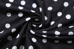 Close-up of black and white polka dot fabric texture with soft draped folds