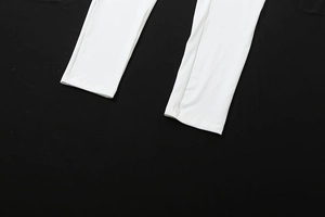 Detail of the white jumpsuit leg cuff showing high-quality double-needle stitching work