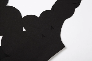 Close-up of black matte dress fabric featuring detailed scalloped edges and cutout design