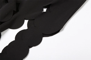 Detail of black summer dress featuring laser-cut hollow wavy edges on high-quality fabric
