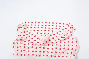 Detailed view of white fabric with red polka dots and layered ruffle texture on the top