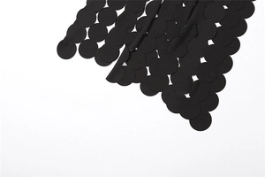 Detail of black dress fabric with laser-cut circular hollow patterns on white background