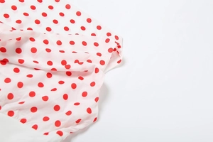 Detail of white semi-transparent chiffon fabric with vibrant red polka dot pattern