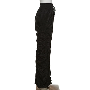 Detailed view of black high-waisted ruched pants with a smooth satin texture and drawstrings