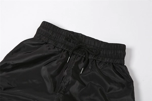 Close-up of black high waist drawstring trousers with elastic band and metal-tipped cords