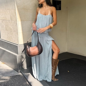Detail of light blue slit dress with waist pleats, leather bag and snake print boots