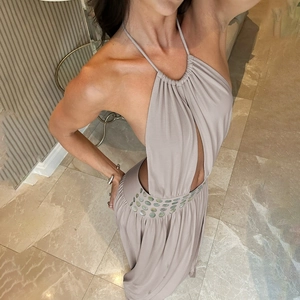 Detail view of the halter neck drapes and decorative shell buttons on a beige maxi dress