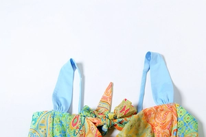 Detail of colorful paisley print top with bow tie and light blue shoulder straps