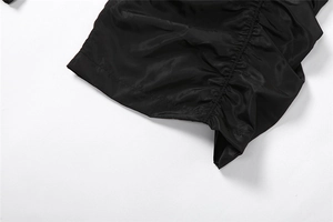 Macro shot of black wide-leg trousers showing detailed ruched high waistband and satin finish