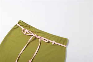 Détail de la taille d'une robe vert olive avec un ruban rose clair noué avec soin