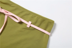 Détail du tissu vert olive montrant le cordon rose et les finitions soignées de la couture