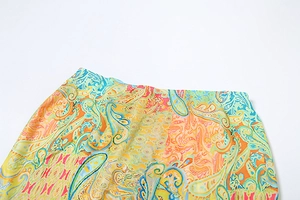 Detail of high-waist paisley skirt with vibrant orange and blue intricate floral patterns