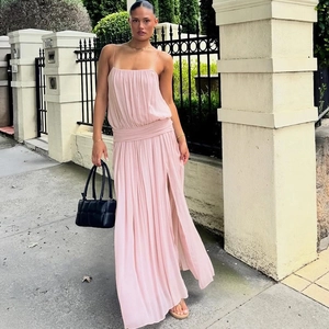 Detail of pink pleated maxi dress featuring high side slit and cinched waist design