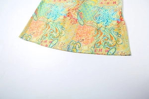 Macro view of paisley print dress hem showing detailed yellow and green swirl patterns
