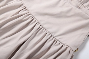 Close-up of ruched fabric texture and decorative wooden button on a beige midi dress