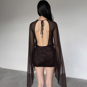 Detail of sheer black mesh dress featuring deep open back and lace-up neck details