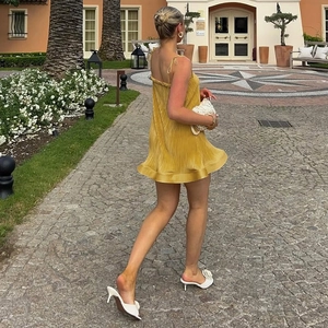 Detail eines mini gelben plissierten Camisole-Kleides mit dünnen Trägern und Rüschensaum