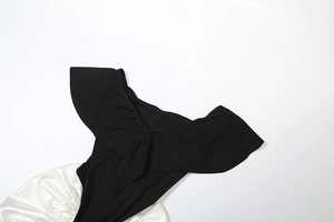 Detail of off-shoulder ruffled black top and white satin skirt contrast dress