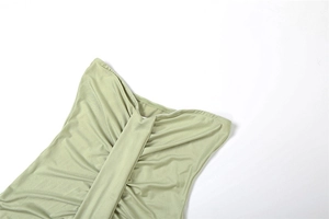 Detailed view of sage green strapless dress with subtle sheen and pleated fabric design