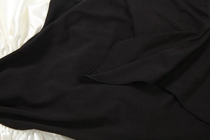 Detail view of the premium black stitching and knit fabric texture of the dress