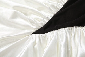 Detail of elegant black and white ruched satin fabric showing refined sewing craft
