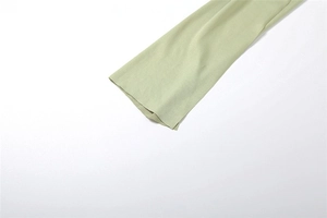 Detailed macro view of light green knitted dress sleeve edge and smooth fabric texture
