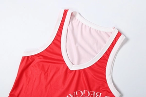 Detail of red athletic V-neck top showing breathable mesh fabric and white piping trim