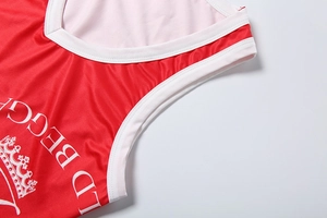 Detail of red athletic top featuring white V-neck trim and crown logo print with smooth stitching