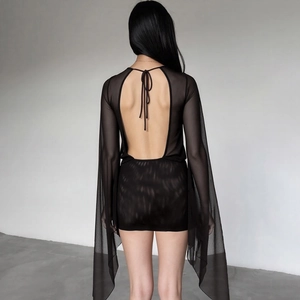 Detail of sheer black mesh mini dress featuring a backless design and neck tie detail