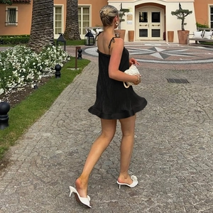 Detail eines schwarzen plissierten Minikleids mit Rüschen und Spaghettiträgern im Resort-Stil