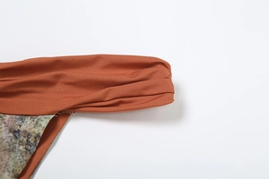 Detail of burnt orange ruched fabric with landscape print texture on a three-piece set