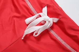 Detail view of red athletic shorts featuring white drawstring bow and high-quality stitching