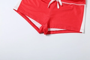 Close-up of red high-waisted sports shorts with side white stripes and drawstring