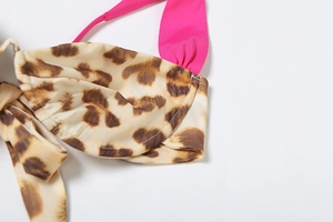 Detailed macro view of leopard print bikini fabric with vibrant pink strap and stitching