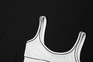 Nahaufnahme eines weißen Sport-Tops mit schwarzen Kontrastkanten und feiner Strickstruktur