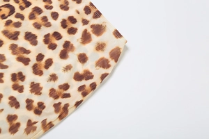Detailed close-up of leopard print chiffon fabric texture with clean stitched hem edges