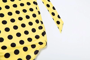 Dettaglio del tessuto giallo a pois neri con spalline elastiche e cuciture rifinite