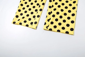 Dettaglio della tuta gialla a pois con cuciture precise sull'orlo e tessuto elasticizzato