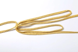 Detailaufnahme goldener Plissee-Stoffträger mit seidigem Glanz und feiner Textur am Kleid