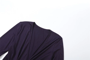 Detail of a deep purple wrap V-neck long-sleeved dress with smooth knit fabric texture